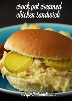 a chicken sandwich on a bun with pickles and ketchup sits on a blue plate