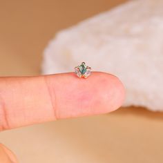 a person's finger with a tiny diamond ring on it