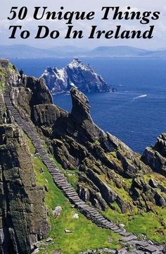 stairs lead down to the top of a rocky cliff by the ocean with snow capped mountains in the background