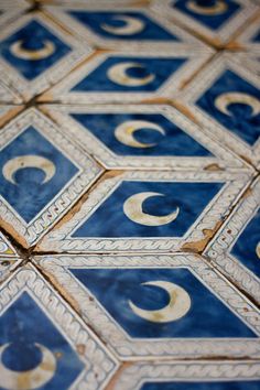 an intricately designed blue and white tile with gold circles on the center is shown