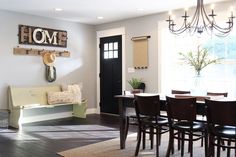 a dining room table with chairs and a bench in front of the door that is open