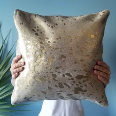 a person holding up a pillow with gold spots on it