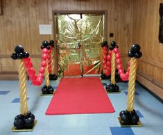 some black and red balloons are in the middle of a room with a red carpet