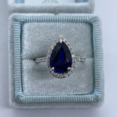 an oval shaped blue sapphire and diamond ring in a white velvet box with silver band