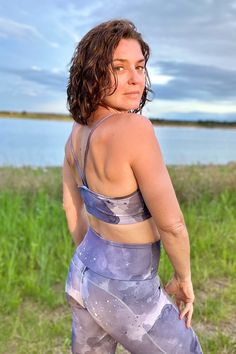 a woman is standing in the grass with her back to the camera and looking off into the distance