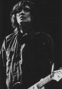 a black and white photo of a man playing an electric guitar