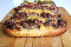 two pizzas sitting on top of a cutting board with cheese and meat toppings