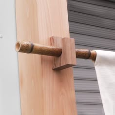 a wooden towel rack with two towels hanging from it's sides and a roll of toilet paper on the other side