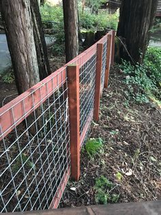 a metal fence is next to some trees