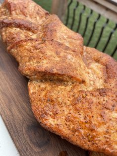 two pieces of meat sitting on top of a wooden cutting board