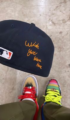 a baseball cap with the words wish you were here written on it next to a pair of sneakers