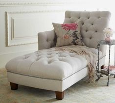 a chaise lounge chair with pillows on it in front of a white painted wall