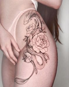 a woman's thigh with a snake and flowers tattoo on it