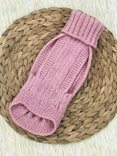 a pink knitted mitt sitting on top of a woven basket