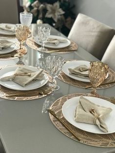 the table is set with white and gold plates, napkins, and silverware