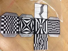 four black and white pieces of paper sitting on top of a wooden table