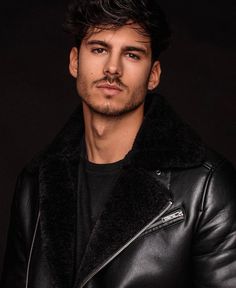 a man wearing a black leather jacket with a fur collar