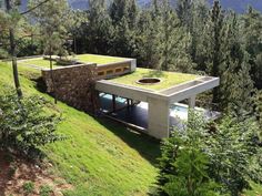 an aerial view of a house in the woods with grass on the roof and windows