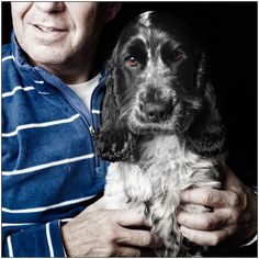 a man holding a black and white dog in his arms