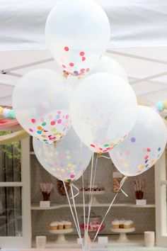 a bunch of white balloons with confetti on them