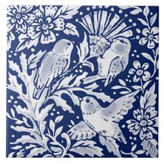 a blue and white tile with two birds on the left side, surrounded by flowers