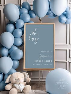 a baby shower sign with balloons and a teddy bear sitting in front of the frame