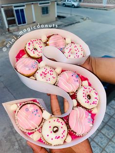 a person holding a box filled with lots of donuts on top of each other