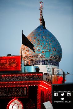 a blue dome with arabic writing on it and a flag flying in the air next to it