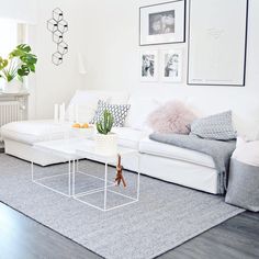 a living room filled with white furniture and pictures on the wall above it's coffee table