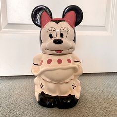 a ceramic mickey mouse figurine sitting on the floor in front of a door