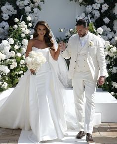 a bride and groom walking down the aisle at their wedding ceremony with white flowers in the background