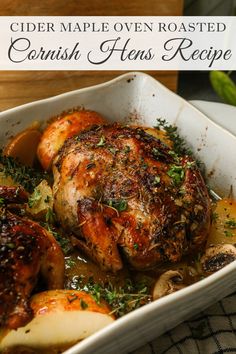 a close up of a chicken in a dish with potatoes and herbs on the side