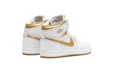 The Air Jordan 1 High OG PS "Metallic Gold" is the preschool sizing of Michael Jordan’s first signature shoe with flashy, head-turning gold details.  On this colorway, the timeless Jordan 1 High OG is designed with a white leather construction.  A Metallic Gold leather Swoosh is seen on each side of the shoe, and a Metallic Gold “Wings” logo appears on the collar.  More Metallic Gold is featured on the collar underlay and “Nike Air” branding on the tongue tag.  Underfoot, a white midsole and gol Gold High-top Basketball Shoes, Nike Yellow High-top Jordan Shoes, Jordan 1 Gold, Sporty Gold High-top Jordan Shoes, Jordan Gold, Metallic Gold Shoes, Jordan 1 High Og, Air Jordan 1 Retro High Og, Air Jordan 1 Retro High