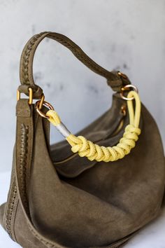 a brown purse with a yellow rope on the handle