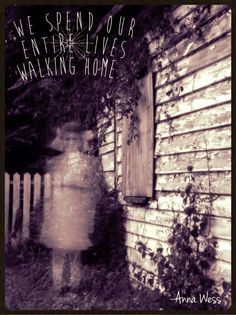 a black and white photo of a person standing in front of a house with vines growing on it