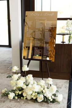 a sign with flowers on the ground in front of it