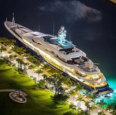 an aerial view of a yacht docked in the water at night with its lights on