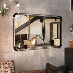 a living room filled with furniture and a mirror hanging on the wall above it's headboard