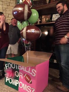 three men are standing in front of a box with footballs on it and balloons