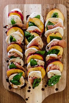 a wooden cutting board topped with sliced peaches and meats on top of it