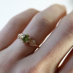 a woman's hand with a ring on it and a green stone in the middle