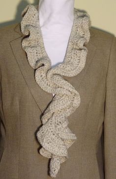 a white mannequin wearing a brown jacket and crochet ruffle scarf