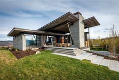 the modern house is located on top of a grassy hill