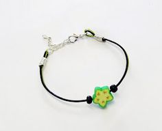 a bracelet with a green and black beaded star charm on the end, sitting on a white surface