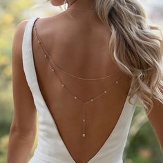 the back of a woman's neck wearing a white dress with pearls on it