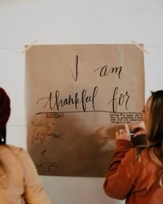 two women standing in front of a sign that says i am grateful for