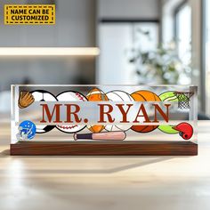 a clear acrylic sign that says mr ryan with basketballs and mitts