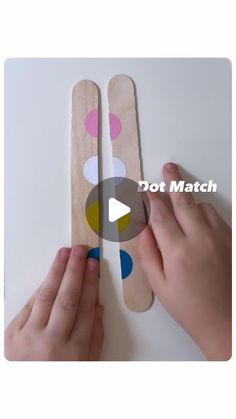 two hands holding wooden spoons with polka dot match on the bottom and one hand pointing at each other