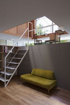 a green couch sitting under a window next to a stair case