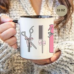 a woman holding a white coffee mug with scissors and combs on it